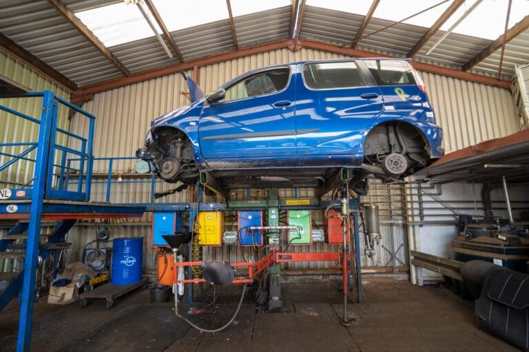 Blauwe auto op hefbrug in werkplaats