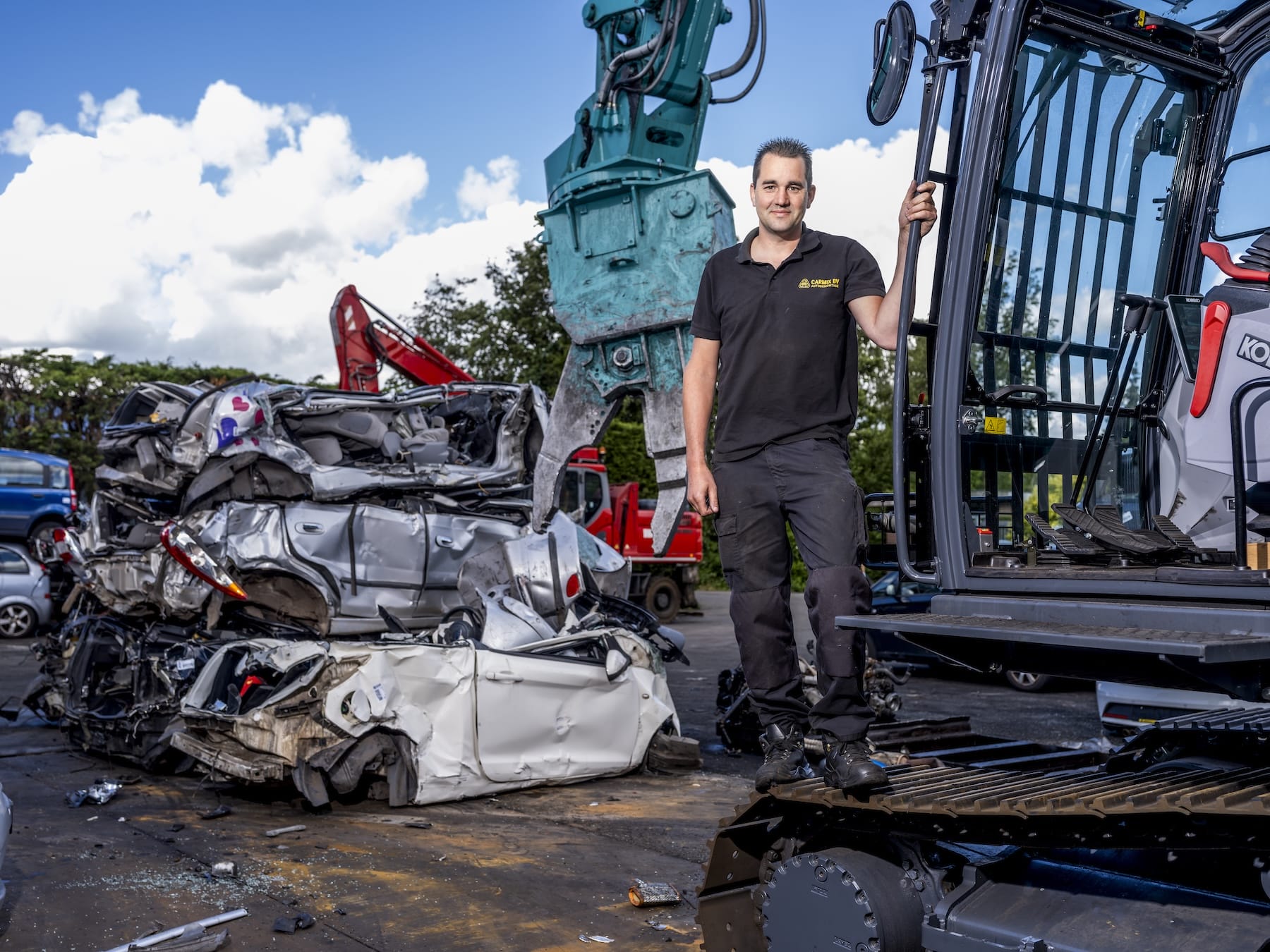 Man bij graafmachine op autosloperij