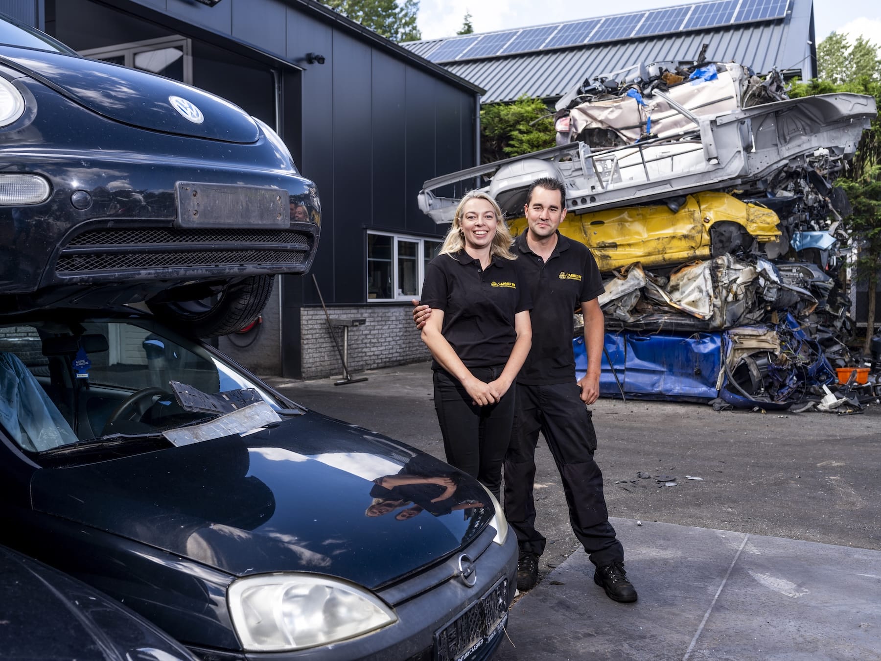 Michael Netten en Jessica Pauw bij autodemontagebedrijf Carmix in Woerden met gestapelde wrakken