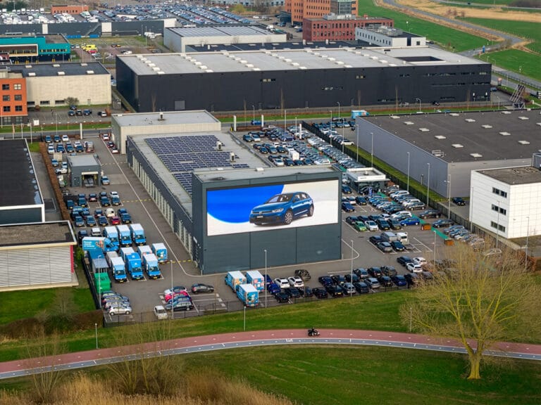 Distributiecentrum met vrachtwagens en geparkeerde auto's.