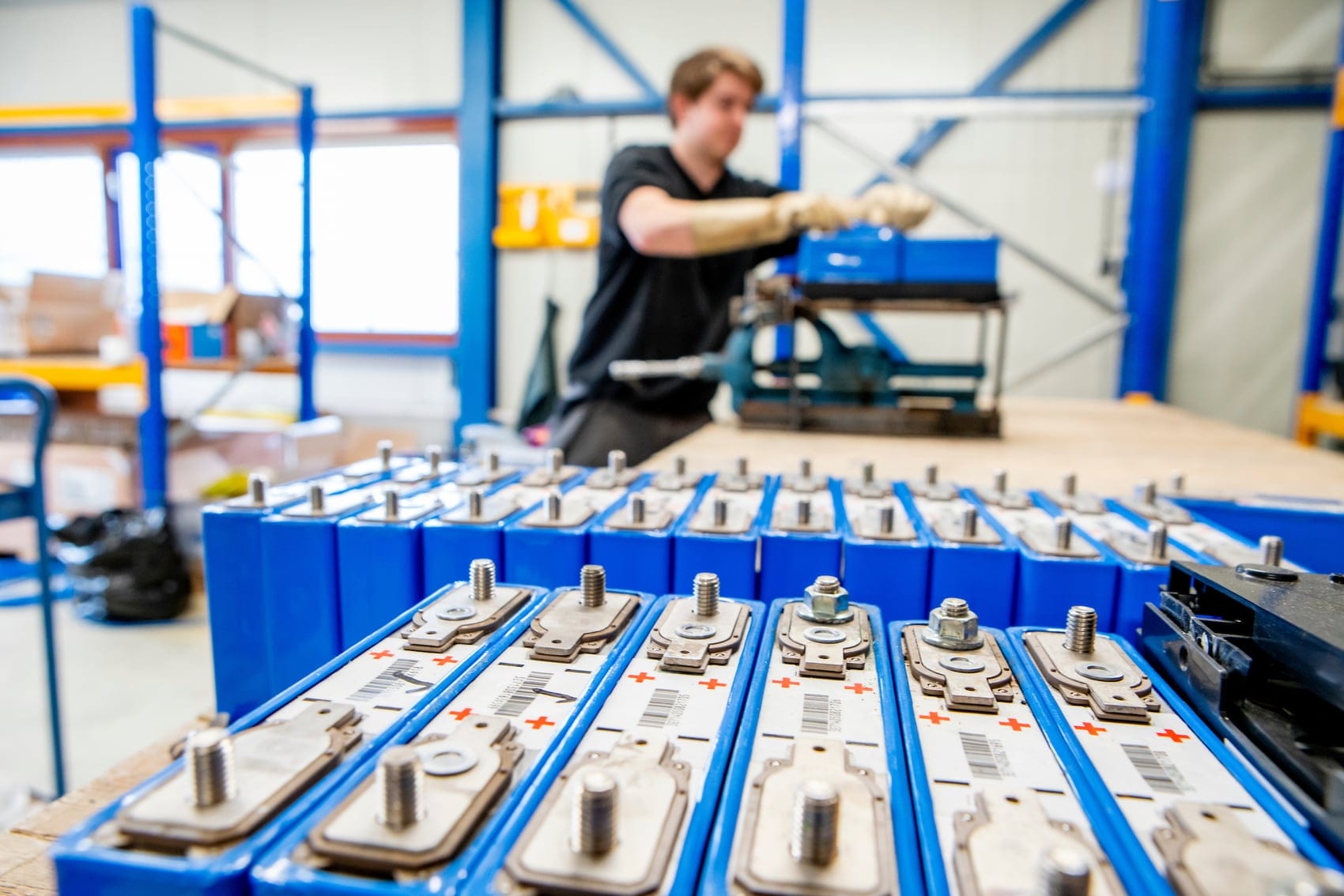 Man assembleert blauwe batterijen in een werkplaats.