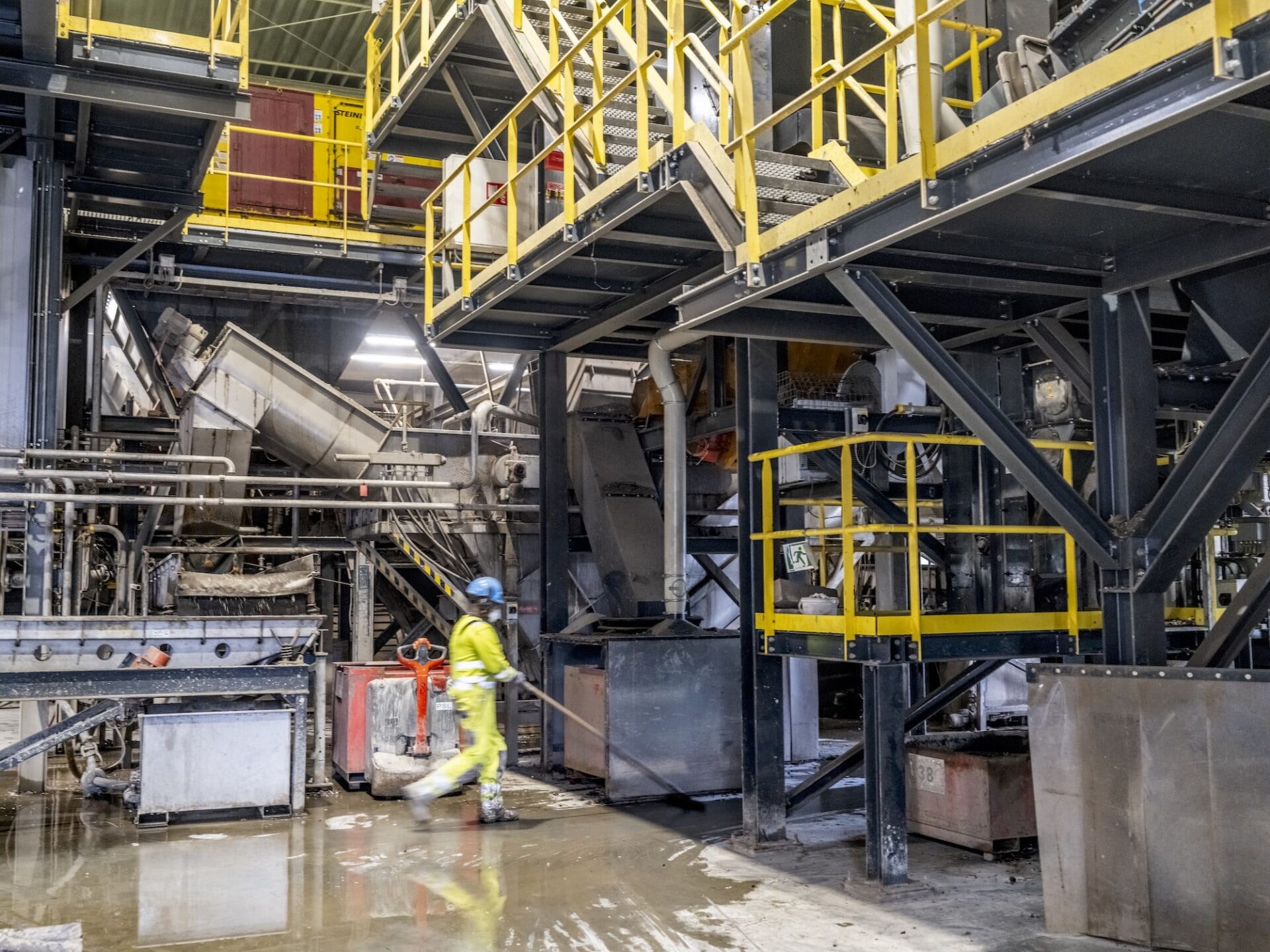 Werker in fabriekshal met machines en staalconstructies.