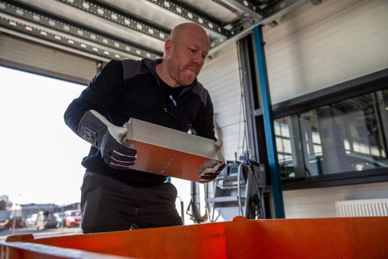Automonteur plaatst een batterij in een oranje container